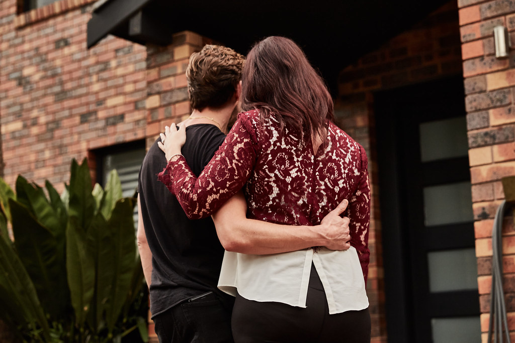 Couple stand in front of home. Photo: Finder.com (BY 2.0, via Openverse)